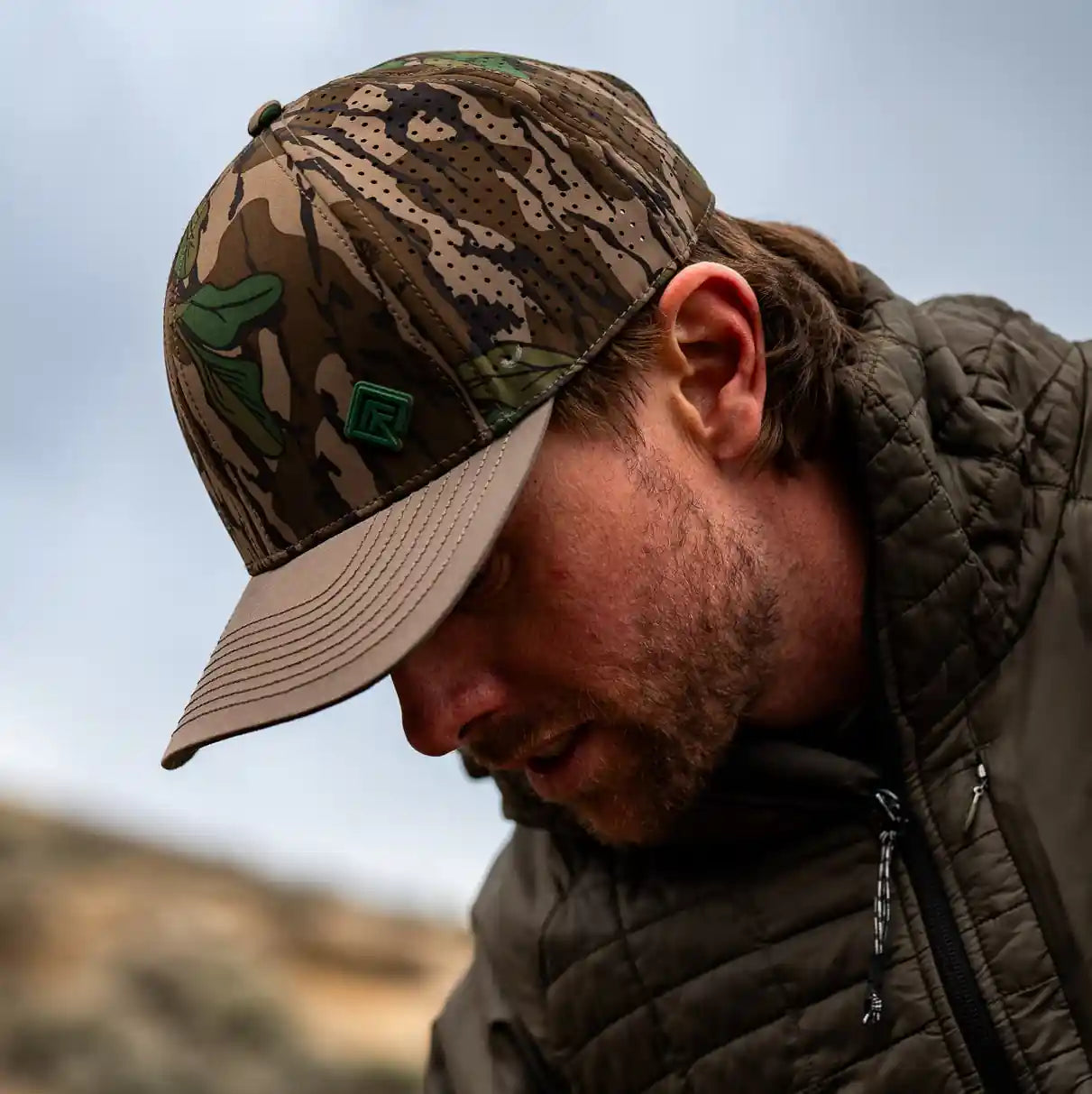 Man in camouflage cap and jacket adjusting bike handlebars outdoors