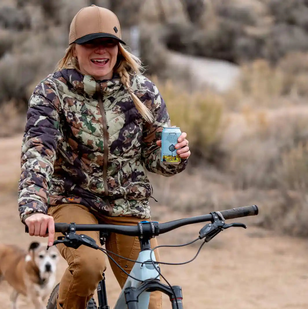 Person riding a bike in a desert-like environment with a dog nearby