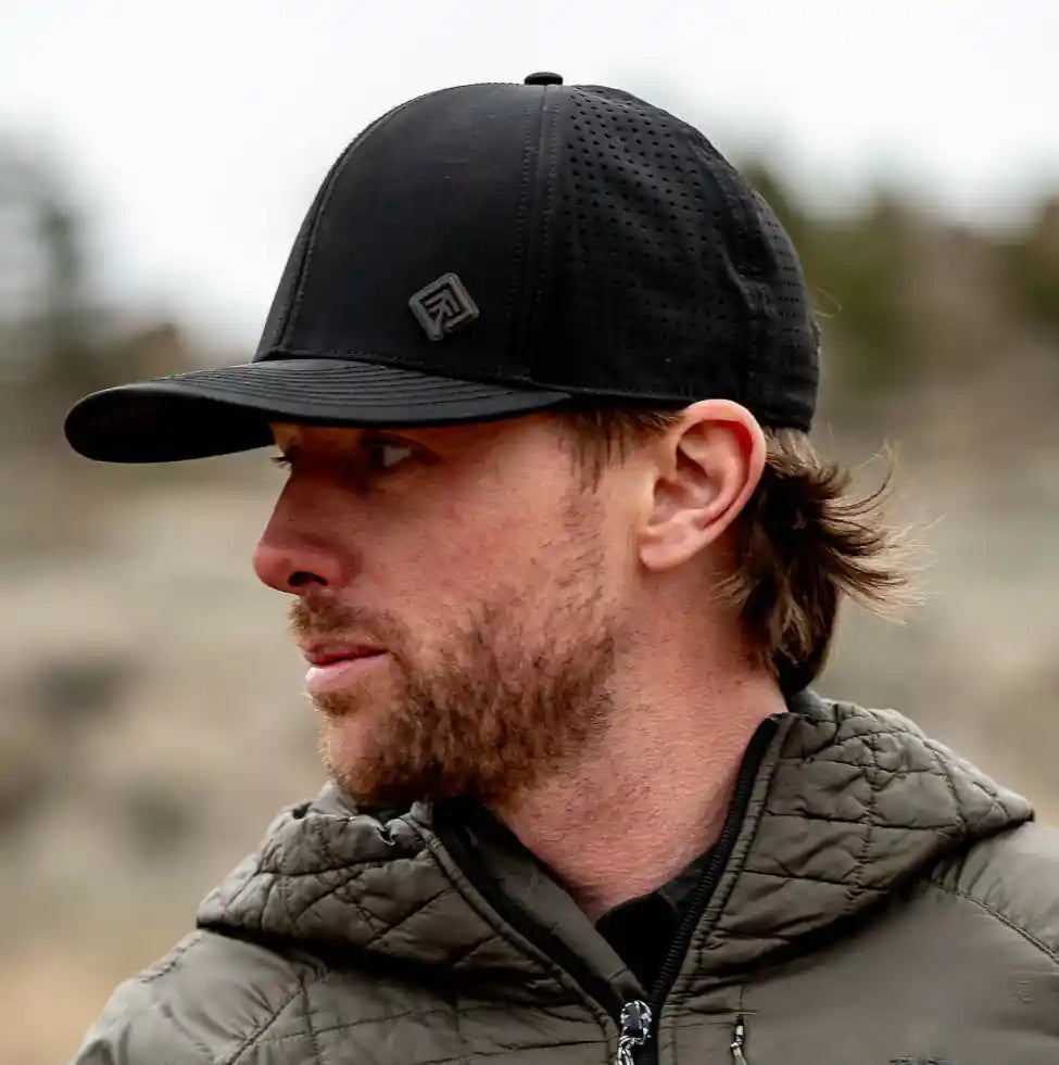 Man wearing a black cap and green jacket outdoors