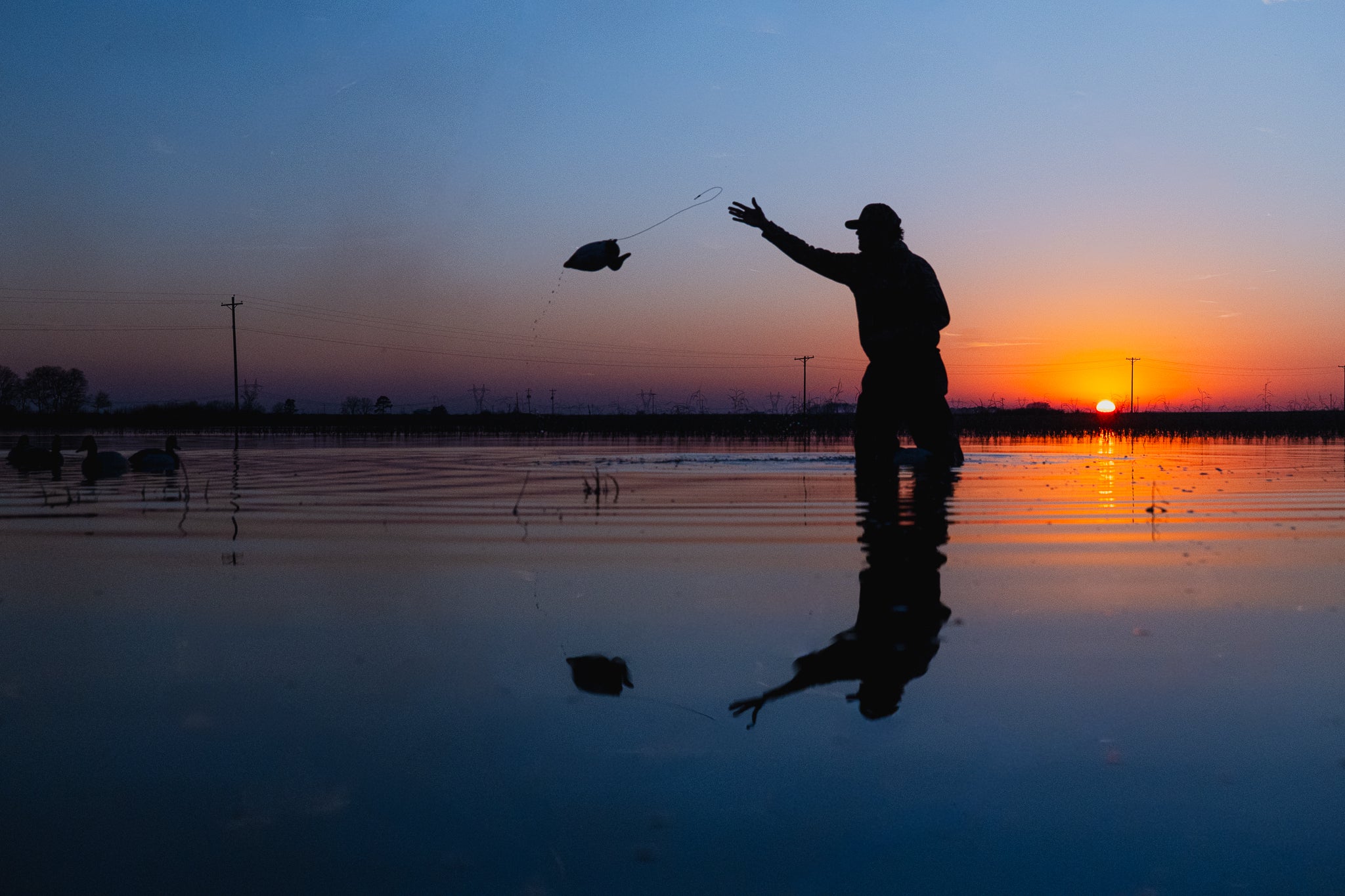 Person standing in shallow water at sunse