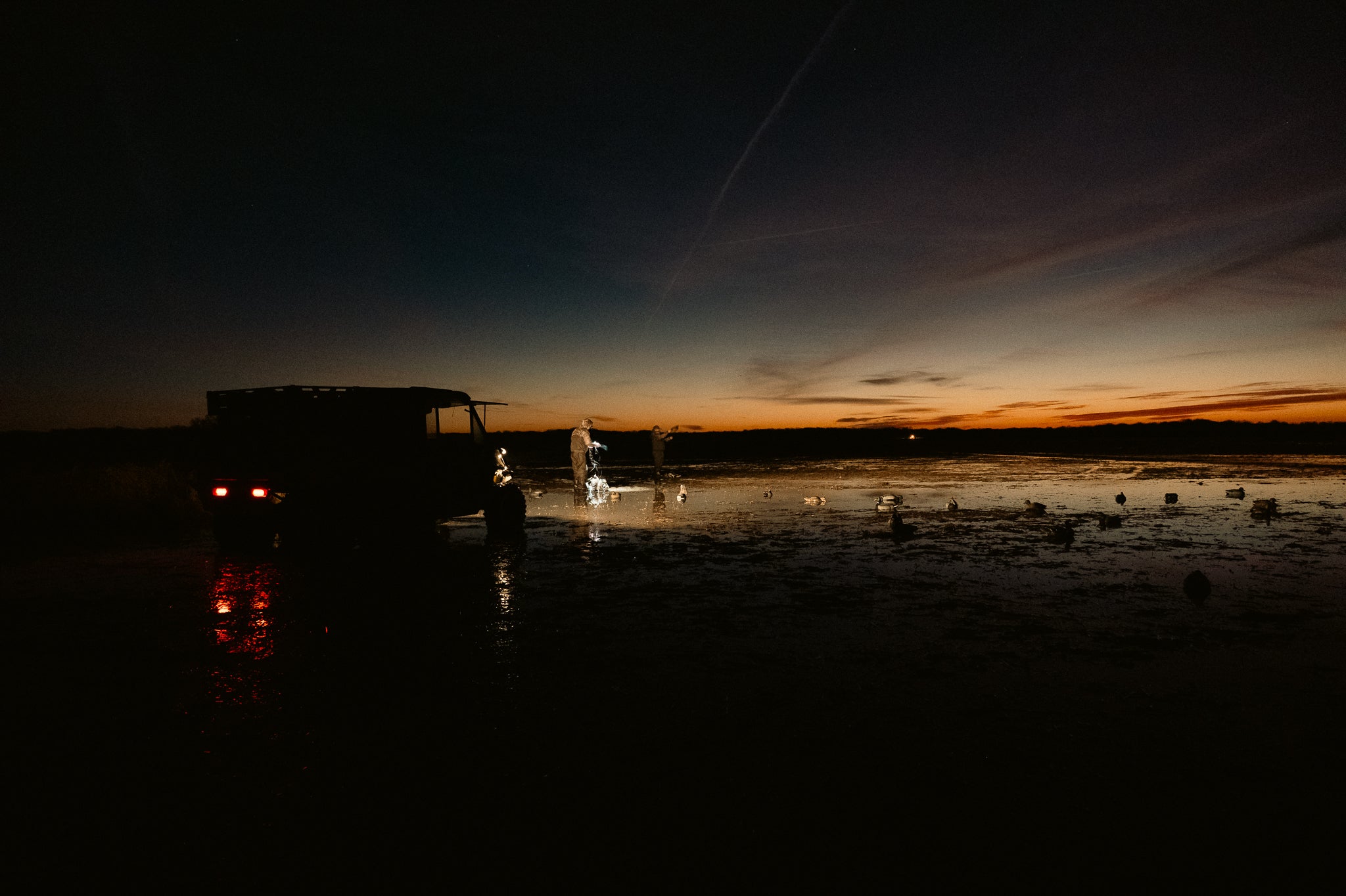 Hat-wearing hunters setting decoys at dawn