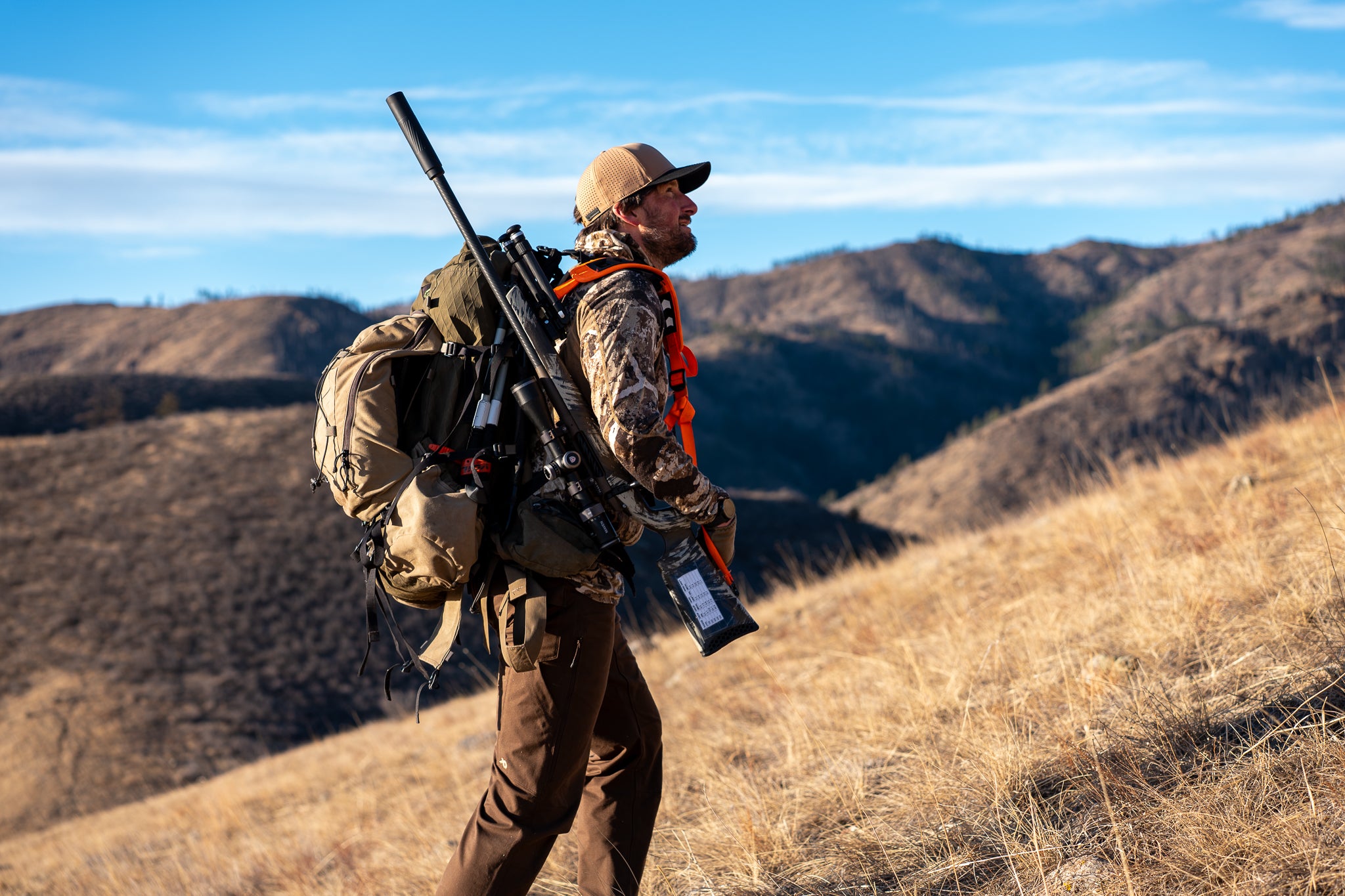 Hunter in tan hat hiking mountain ridge