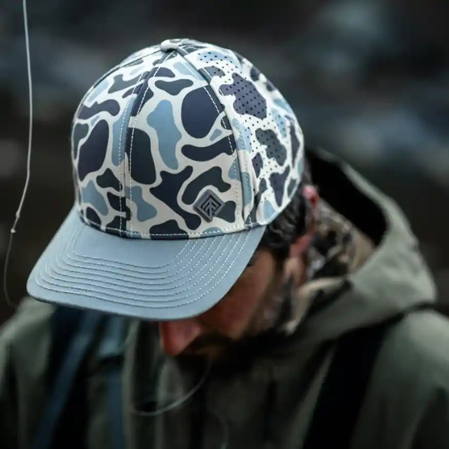 Person wearing a camouflage cap and dark jacket with a blurred background