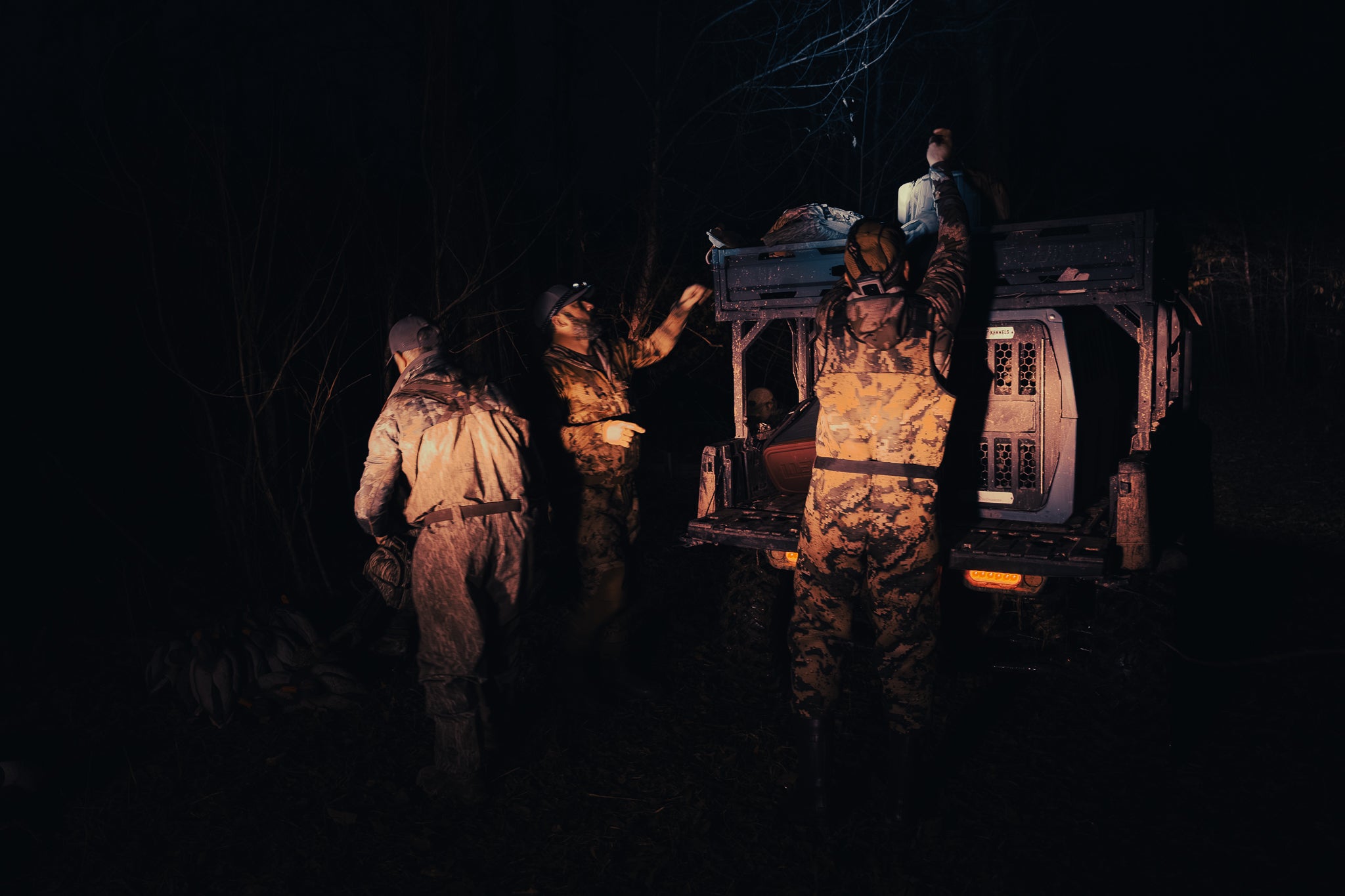 Hunters in hats loading truck at night