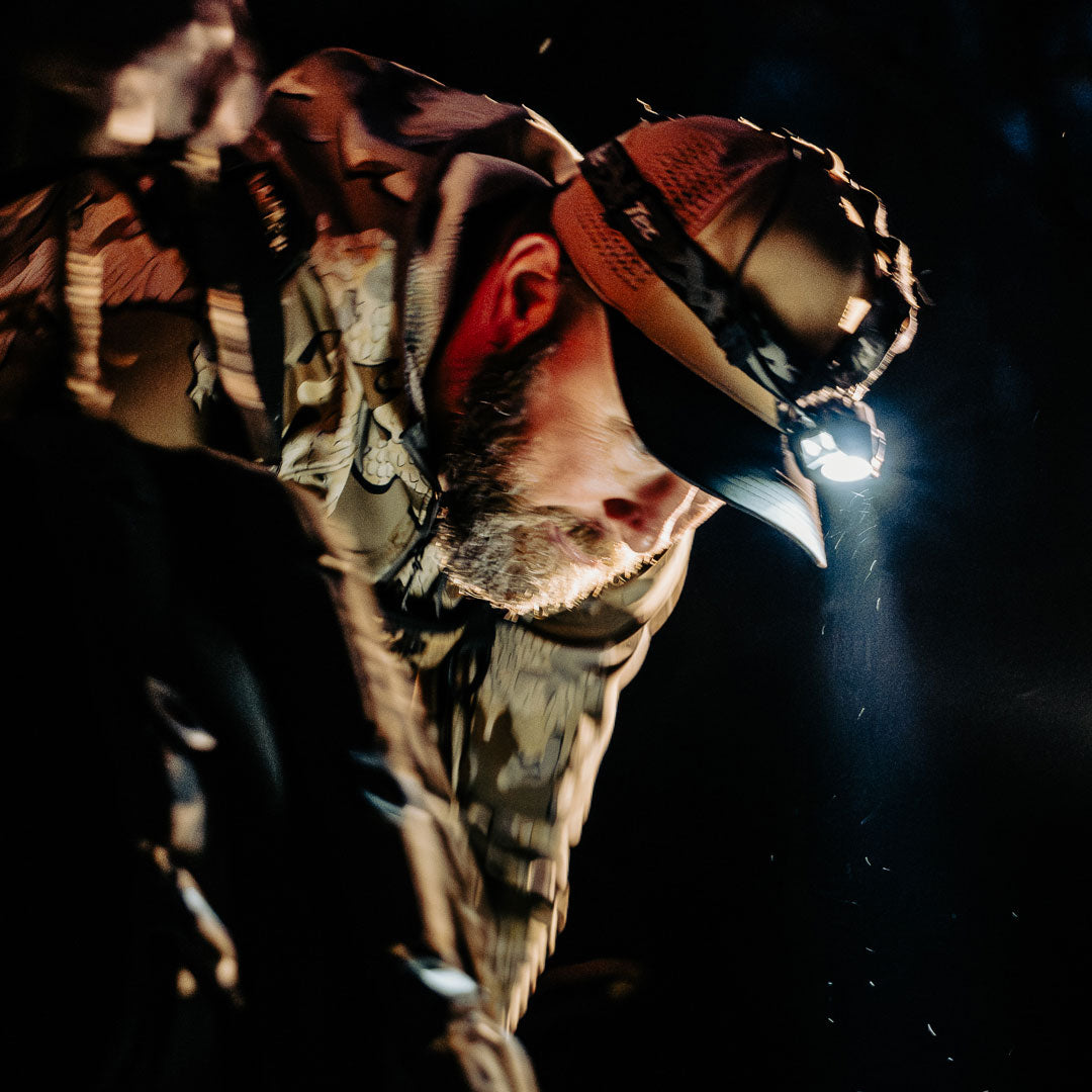 Hunter in camo hat with headlamp at night
