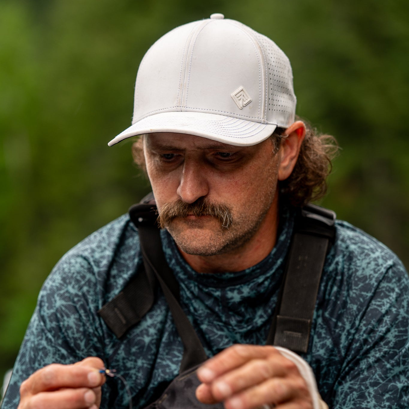 Man preparing fishing equipment with a blurred green background