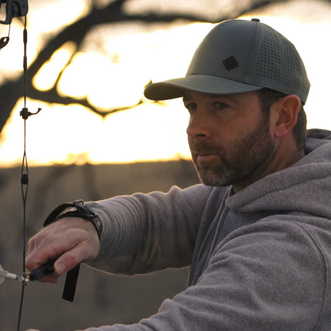 Man preparing a bow and arrow with a sunset in the background