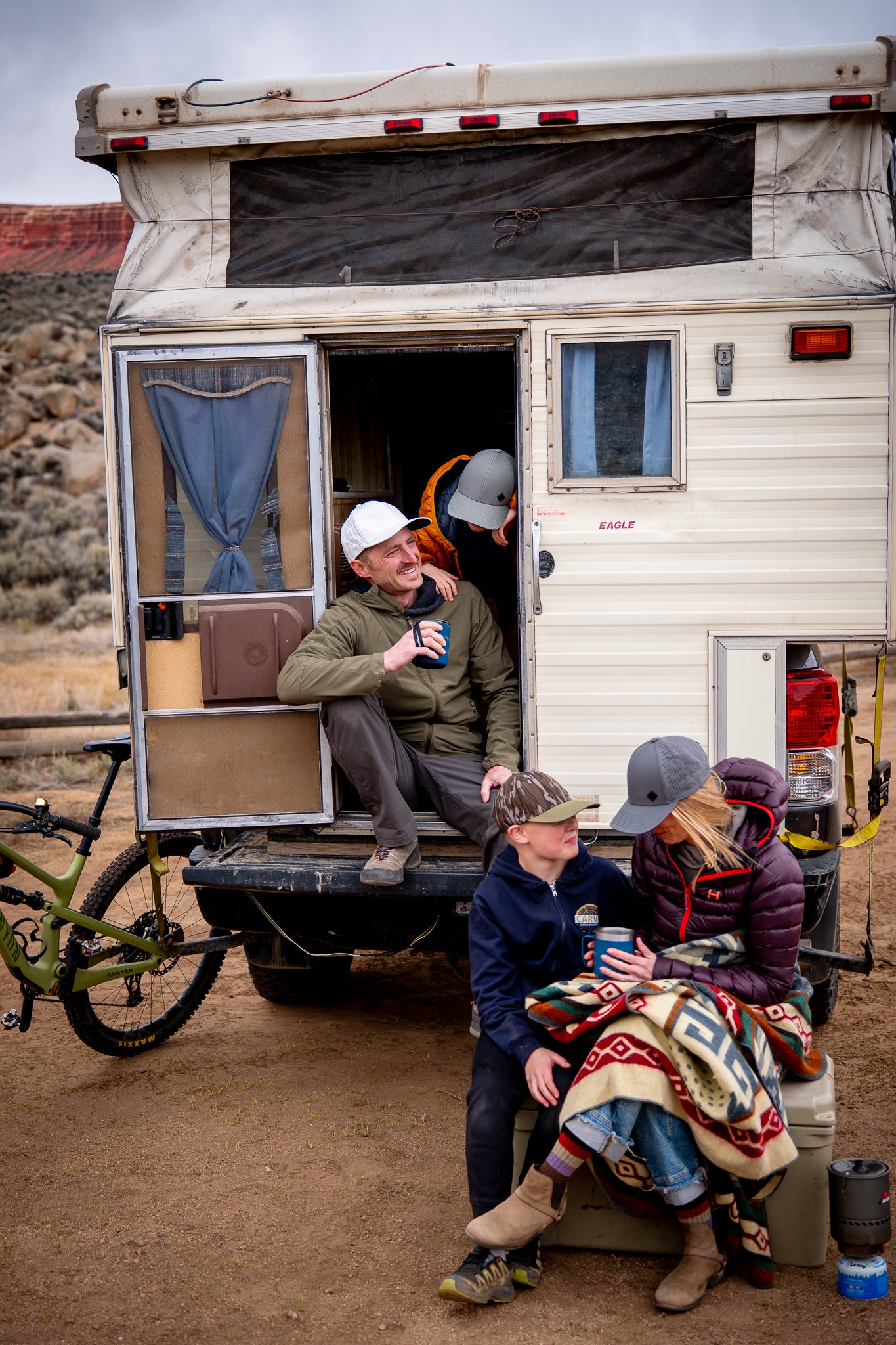 Family in hats relaxing by camper