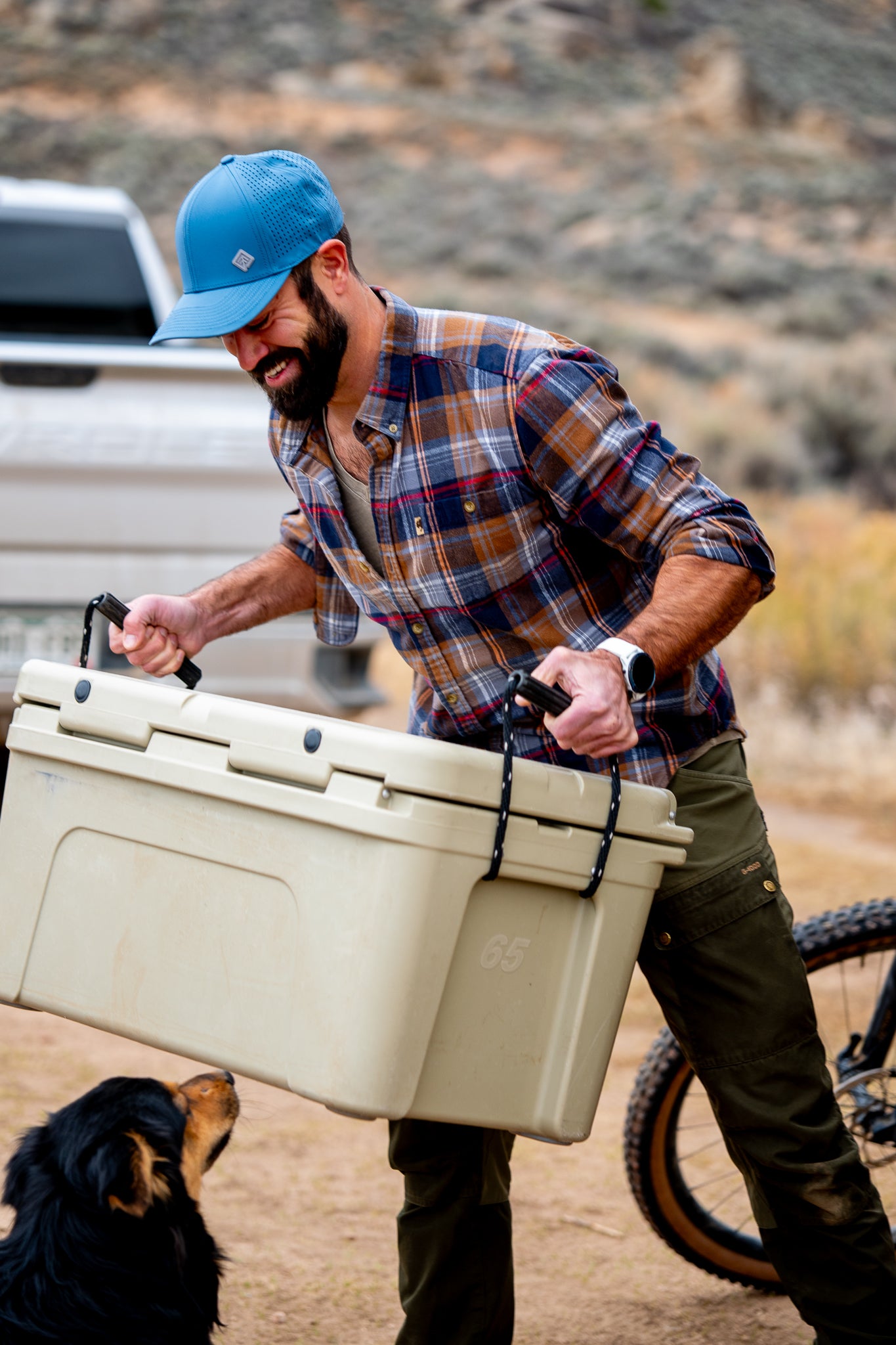 Man in blue hat carrying cooler