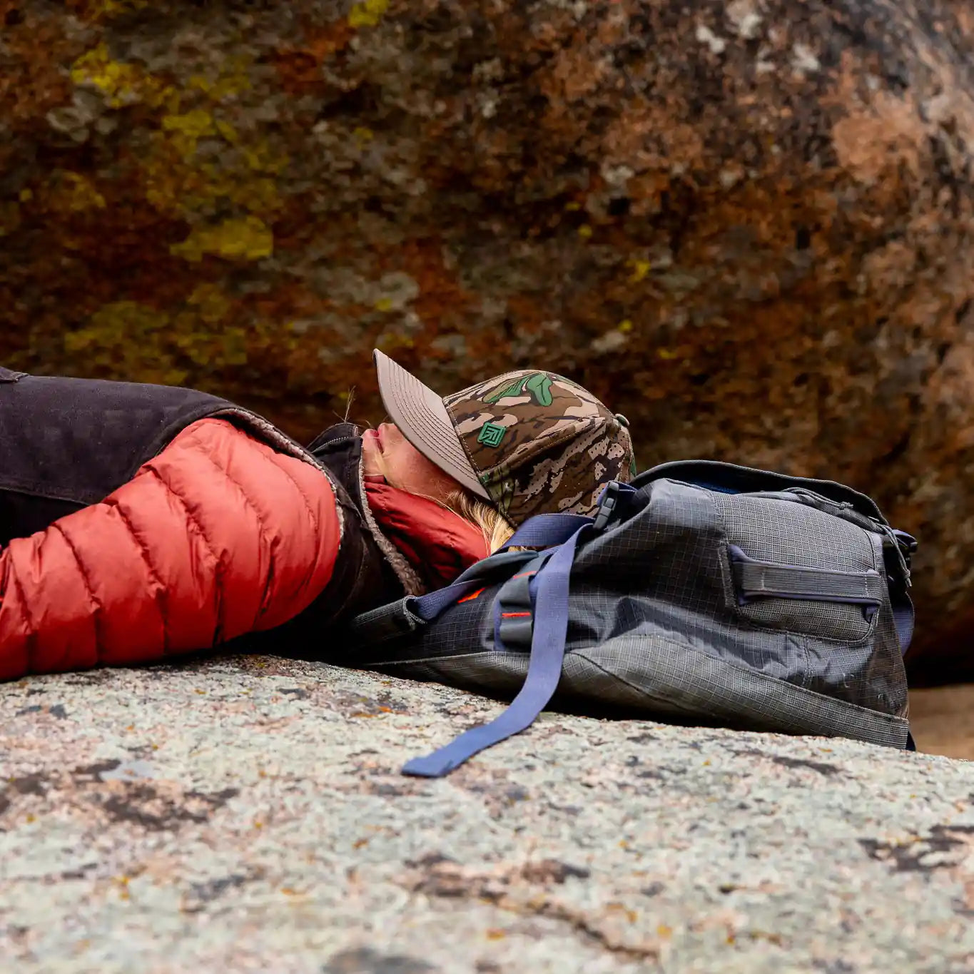 Woman resting on rock in camo hat