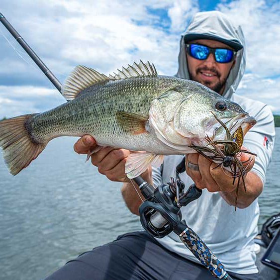 Angler in hat holding caught bass