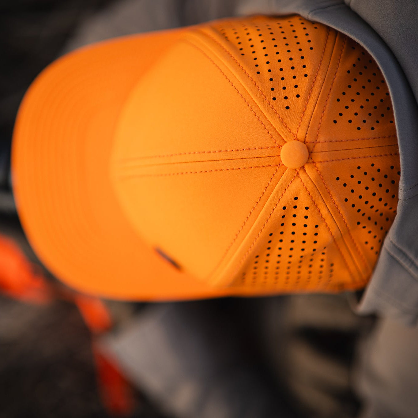 Orange cap with a textured surface worn by a person, blurred background