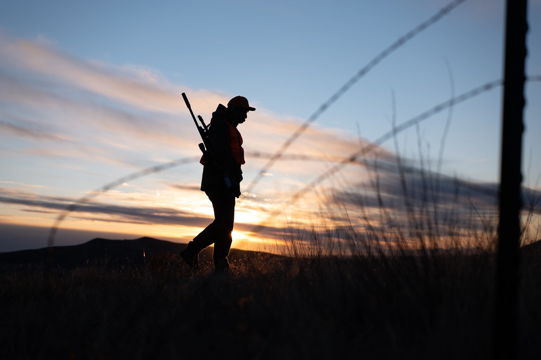 Hunter in hat silhouetted at sunset