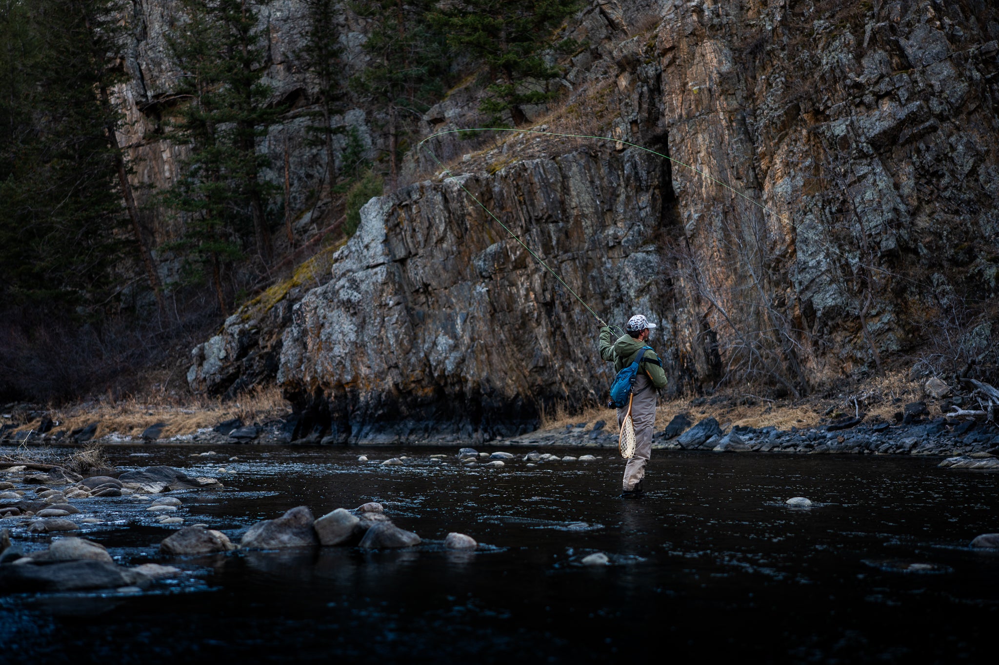 Fly fisherman in river wearing camo Terreno hat