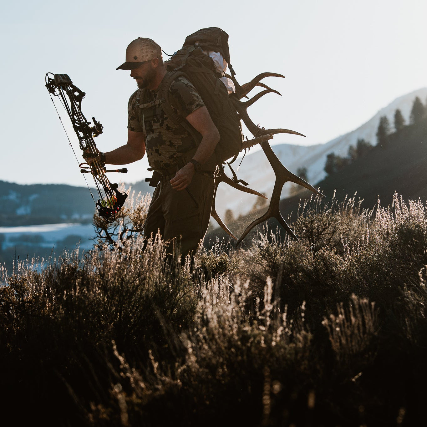 Hunter with bow and backpack in a mountainous landscape