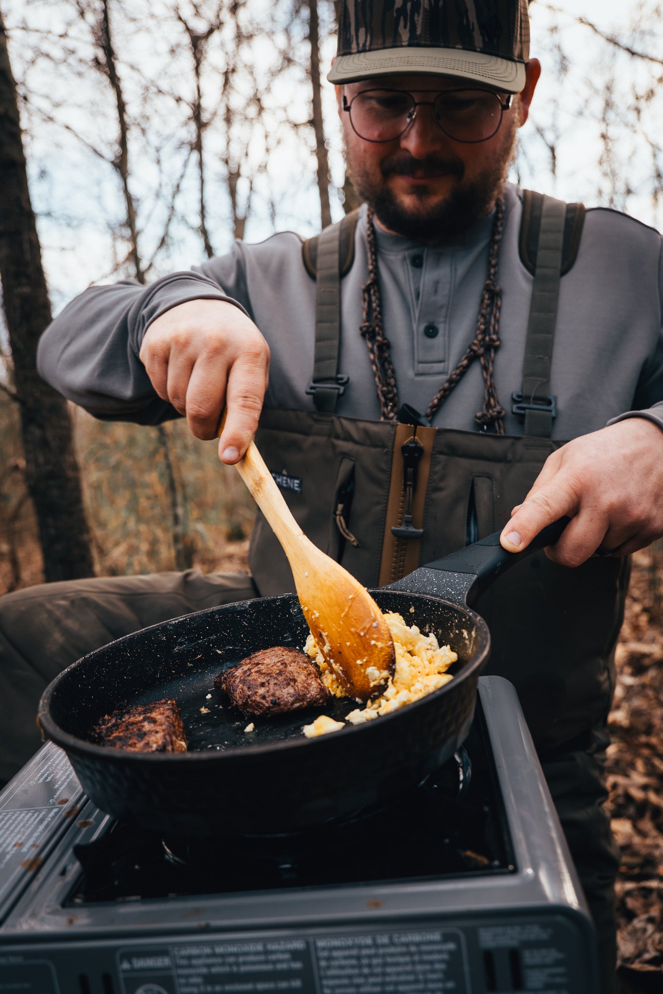 Hunter in camo hat cooking camp breakfast
