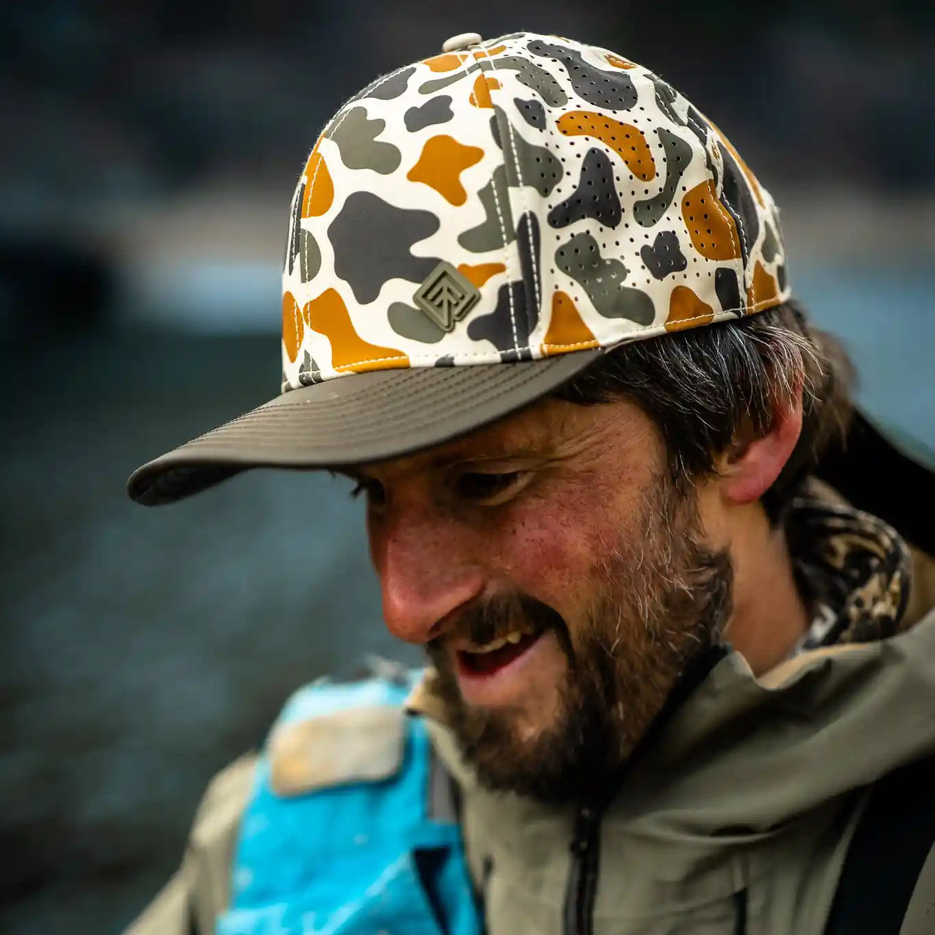 Man wearing a camouflage cap and blue backpack outdoors