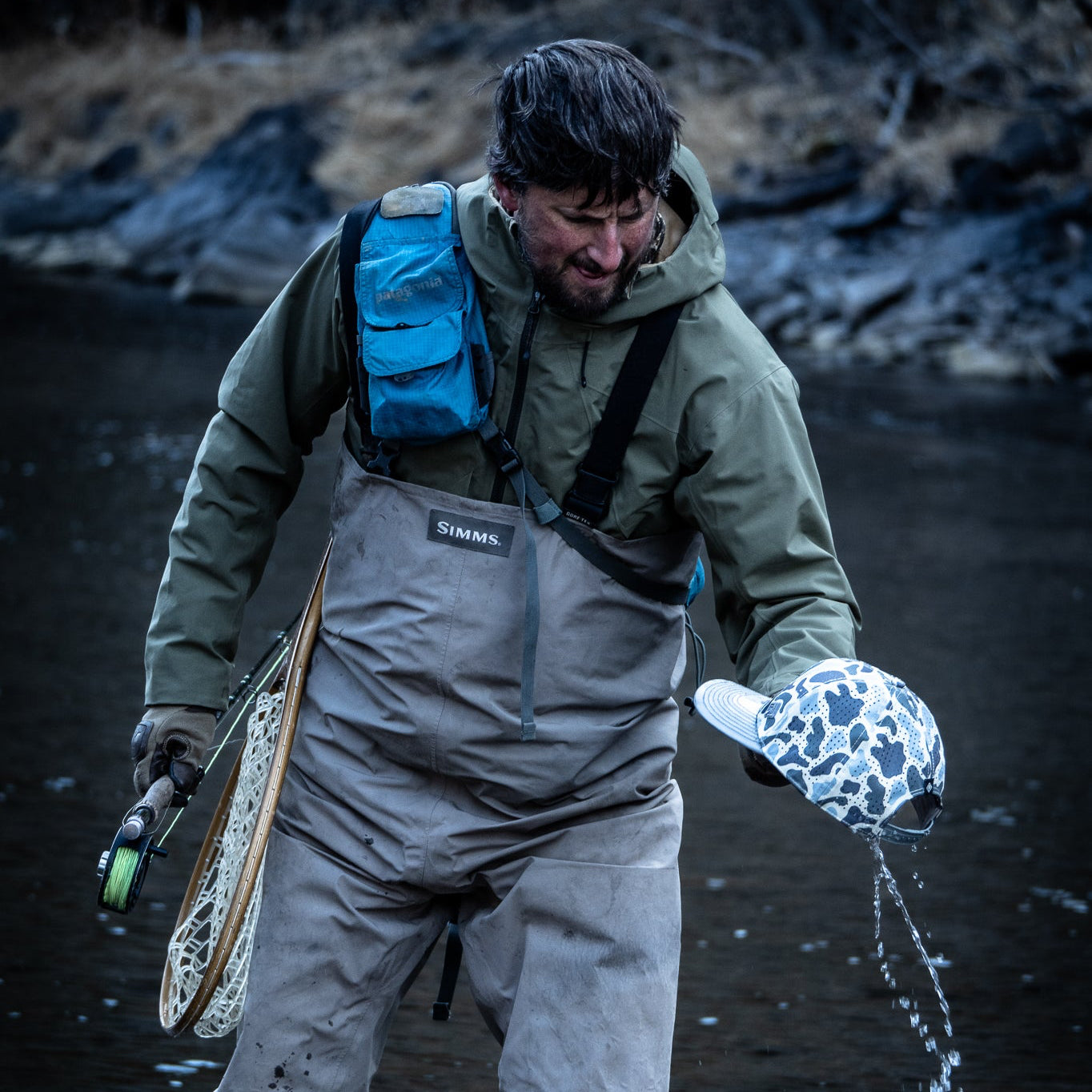 Fisherman wringing water from camo hat