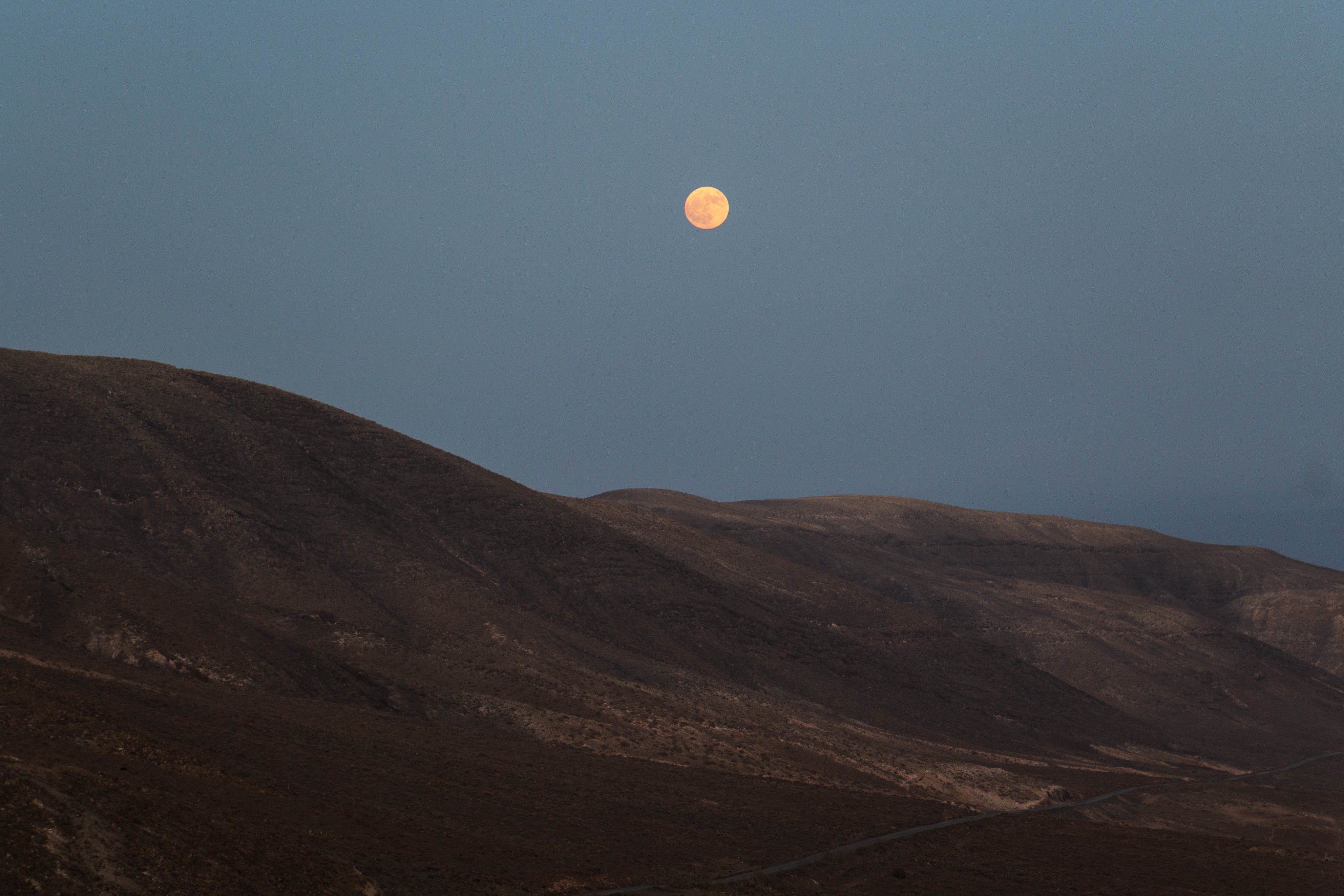 Full moon rising over mountain ridge