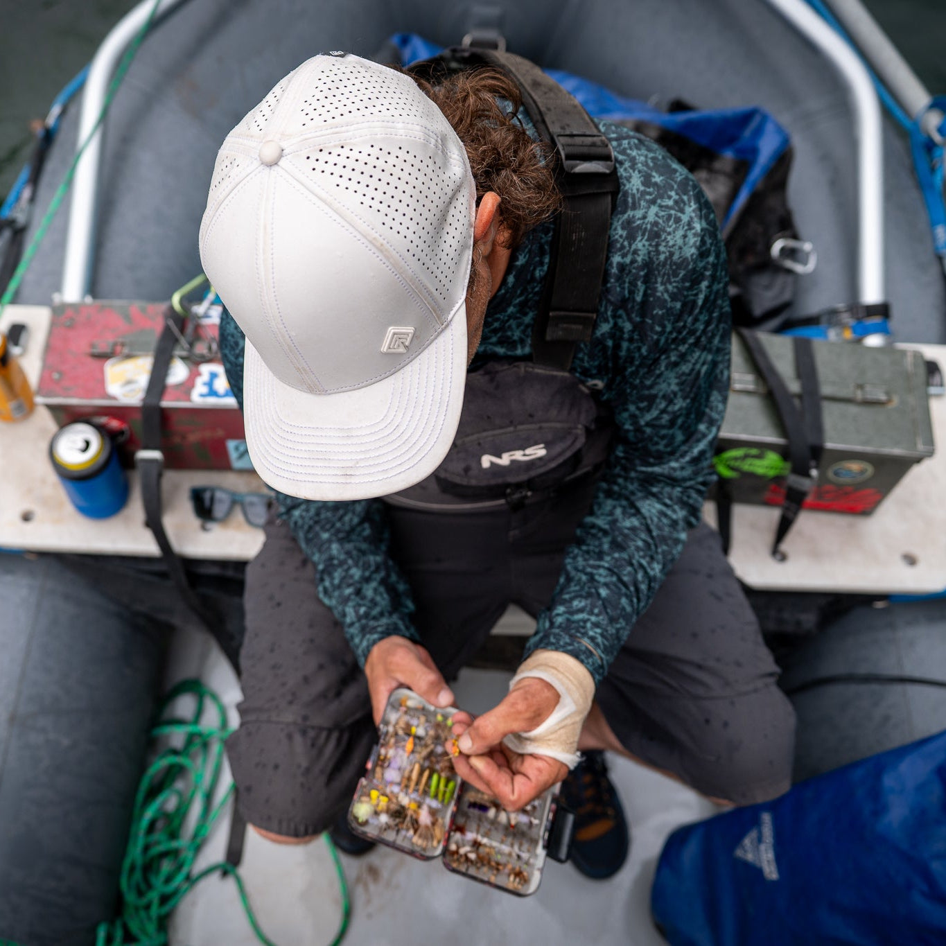 Person on a boat holding fishing lures with fishing equipment around